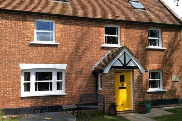 White uPVC sliding sash windows and a yellow composite door